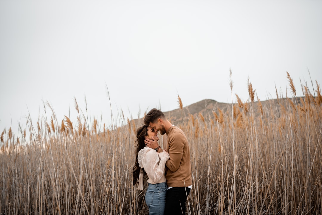 Couple holding broken heart halves on pink background